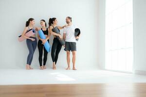 en grupp av kvinna och manlig idrottare stod och chattade i godo i de studio innan början med de yoga klass. foto