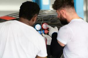 bil mekaniker arbetssätt i ett bil reparera affär, inspekterande de drift av de bilens luft balsam och kylmedel. foto