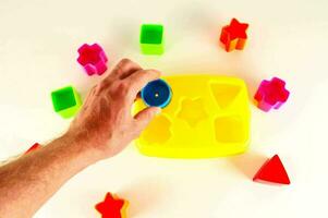en hand är innehav en plast leksak med färgrik former foto