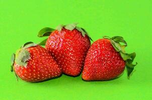 tre jordgubbar är visad på en grön bakgrund foto