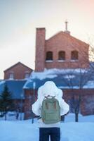 kvinna turist besöker i sapporo, resande i Tröja ser sapporo öl museum med snö i vinter- säsong. landmärke och populär för attraktioner i Hokkaido, japan. resa och semester begrepp foto