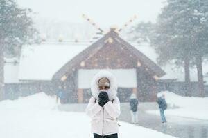 kvinna turist besöker i sapporo, resande i Tröja ser hokkaido helgedom med snö i vinter- säsong. landmärke och populär för attraktioner i Hokkaido, japan. resa och semester begrepp foto