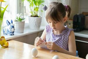 liten flicka dekorera påsk ägg på Hem. framställning för påsk begrepp. selektiv fokus foto