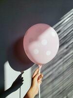 ljus rosa reste sig ballong i hand, ett person innehav en ljus rosa ballong i deras hand. foto
