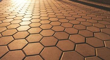 geometrisk mönster bakgrund och textur av sexhörning brun kullersten trottoar i årgång stil med gyllene solljus och skugga på yta foto