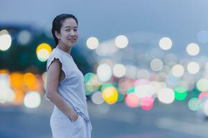 porträtt av Lycklig leende asiatisk kvinna med bokeh ljus i bakgrund. foto