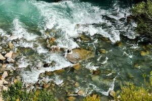 en flod med stenar och vatten strömmande över den foto