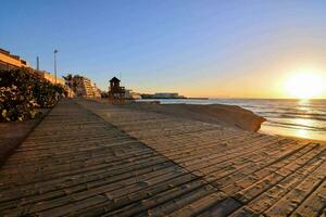 en trä- gångväg leder till de strand på solnedgång foto