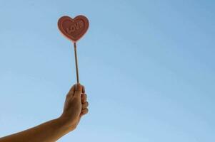 en person innehav en hjärta formad klubba mot en blå himmel foto