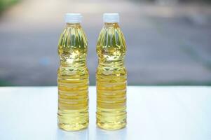 två flaskor av vegetabiliska olja för matlagning. extraherad från frön eller från Övrig delar av växter, sådan som solros frön, soja bönor, oliv, handflatan frukter. utomhus- bakgrund. foto