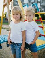 ai genererad söt liten blond barn i en vit t-shirt och blå jeans är spelar på de lekplats foto