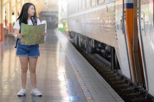 en ung kvinna med en karta står på perrongen och stirrar på tåget. foto