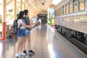 två tonårsflickor som tittar på kartor för att resa med tåg. foto