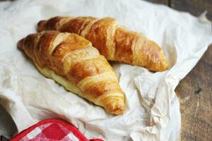 en lugg av utsökt färsk croissanter eras med Smör. på de naturlig trä tabell foto