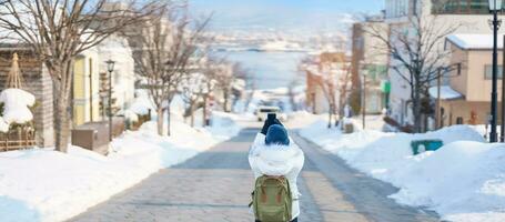 kvinna turist besöker i hakodate, resande i Tröja sightseeing hachiman zaka backe med snö i vinter. landmärke och populär för attraktioner i Hokkaido, japan. resa och semester begrepp foto