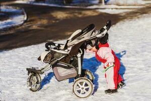 liten bebis skjuter hans sittvagn i vinter- foto