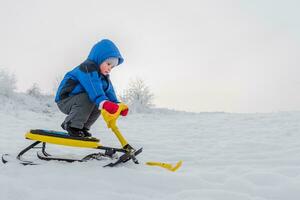 liten barn ridning en snö skoter i vinter- foto