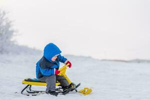 liten barn ridning en snö skoter i vinter- foto