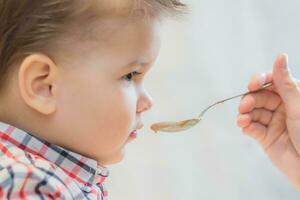 mamma matar de bebis bovete gröt i de kök foto