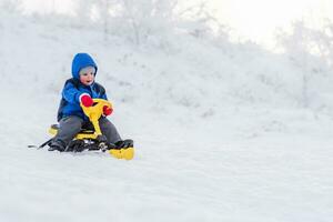 liten barn ridning en snö skoter i vinter- foto