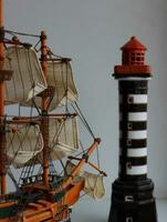 tillbaka vinkel se av skala modell av segling fartyg mot de leksak fyr torn foto