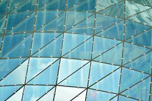 strukturell glas vägg reflekterande blå himmel. abstrakt modern arkitektur fragment foto