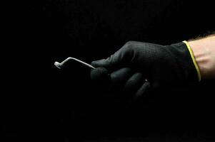 en person i svart handskar innehav en verktyg foto