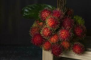en knippa av rambutan frukt på en trä- hylla foto