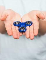 ung man spelar med en fidget spinnare, fokus på hand. foto