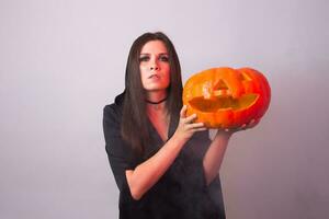 halloween häxa innehav en orange pumpa domkraft o lykta med rök foto