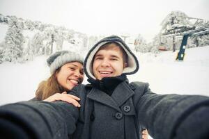 Lycklig pojkvän och flickvän framställning selfie på en vinter- natur foto