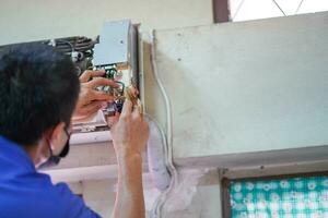närbild elektrisk reparera tekniker fixera ett elektronisk styrelse av hemmets luft balsam. foto