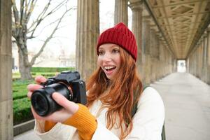 leende turist fotograf, tar bild under henne resa, innehar professionell kamera och gör foton