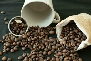 kaffe bönor i påfyllningsbar kaffe kapslar, kaffe påsar och runt om på en svart bakgrund. foto