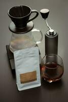 kaffe böna förpackning för droppa kaffe och kaffe böna kvarn på en trä- svart tabell. foto