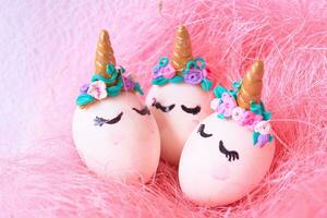 tre påsk ägg unicorns i en rosa bo foto