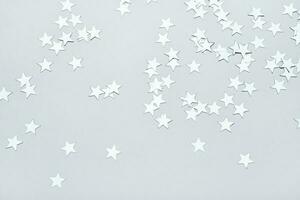 silver- stjärnor konfetti på grå bakgrund. jul eller vinter- festlig bakgrund foto