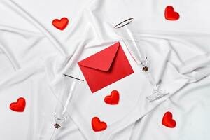 romantisk begrepp. valentines dag bakgrund. röd kuvert, champagne glasögon och hjärtan på vit silke ark foto