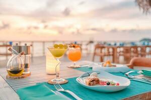 lyxig frukostmat färsk juice på träbord, med vacker tropisk resort och havsutsikt bakgrund, morgontid sommarsemester och romantisk semester koncept, lyxresor och livsstil humör foto