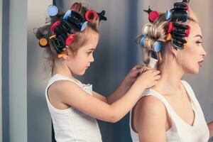 skön ung mor och henne dotter med hår papiljotter foto