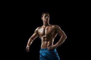 muskulös och passa ung kroppsbyggare kondition manlig modell Framställ över svart bakgrund. foto