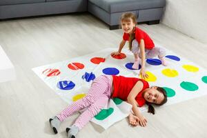 två liten flickor har roligt spelar spel på golv på Hem. syskon vänskap foto