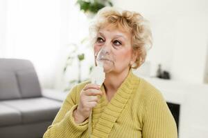äldre kvinna använder sig av astma maskin på ljus bakgrund foto