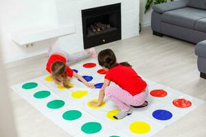 två liten flickor har roligt spelar spel på golv på Hem. syskon vänskap foto