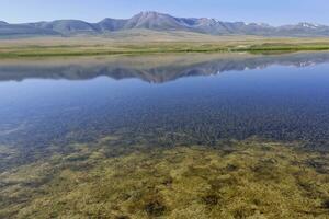 bergen reflekterande i en sjö längs de på-bashy räckvidd, naryn område, kyrgyzstan foto