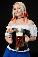 ung sexig kvinna bär en dirndl med öl råna på svart bakgrund. foto
