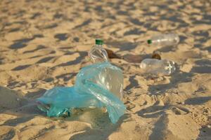 blå väska med sopor lögner på strand av pittoresk flod, skrynkliga plast flaskor är spridd närliggande. rengöring upp skräp. volontärarbete. närbild. foto