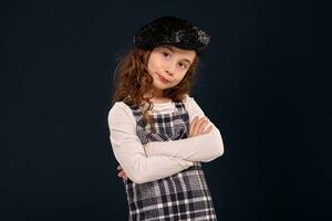 eleganta brunett unge är Framställ i studio på en svart bakgrund. barns mode. foto
