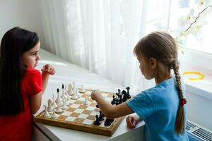 två söta barn som spelar schack hemma foto