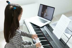 liten flicka distans inlärning de piano uppkopplad under karantän. coronavirus begrepp. foto